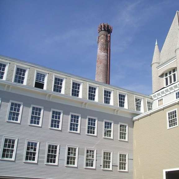 a building with a tall chimney and a tower with a pointed roof.