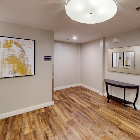 a hallway with a wooden floor and a painting on the wall.