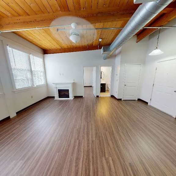a spacious room with wooden floors and white walls.