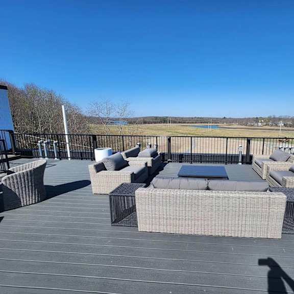 a patio with a table and chairs overlooking a field.