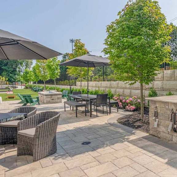 a patio with a grill and chairs.