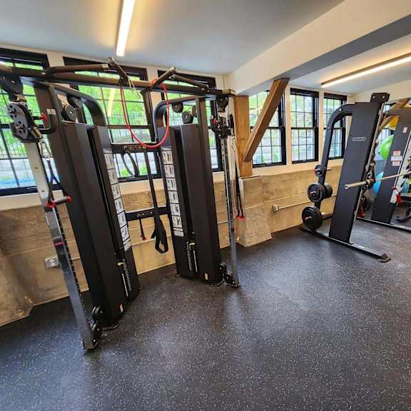 a gym with a variety of equipment including a squat rack, a leg press machine, and a cable machine.