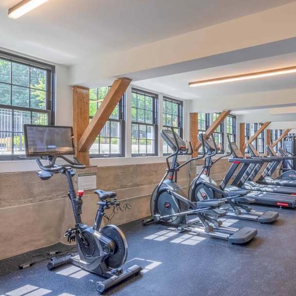 a gym with a row of stationary bikes and treadmills.