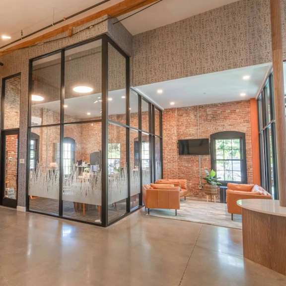 a room with a glass wall divider and a brick wall.