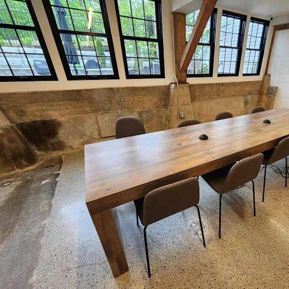 a long wooden table with chairs is in a room with a black door.