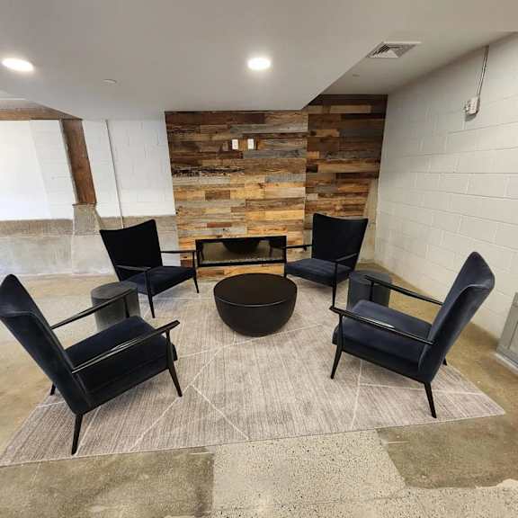 a room with a stone wall and a round table surrounded by chairs.