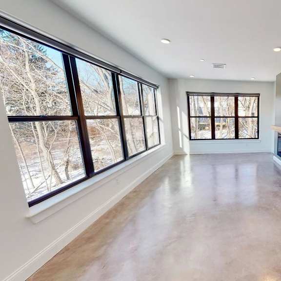 a large, empty room with a view of trees outside the windows.