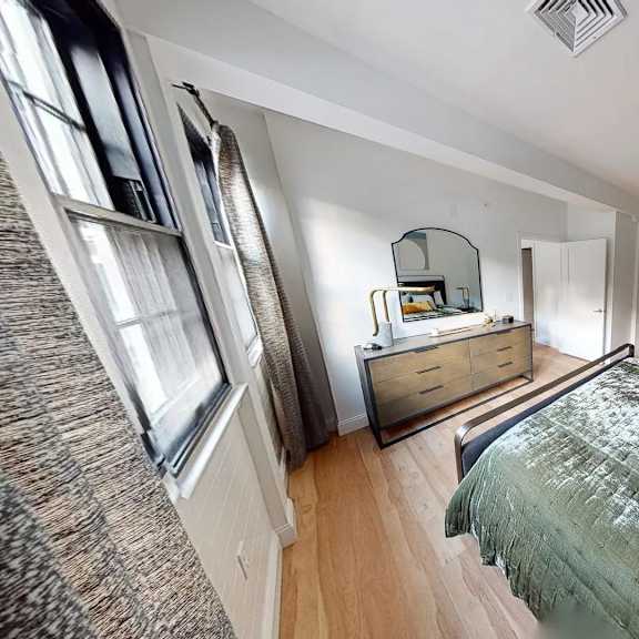 a bedroom with a bed, dresser, and mirror.