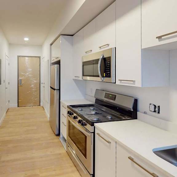a kitchen with white cabinets and a wooden floor.