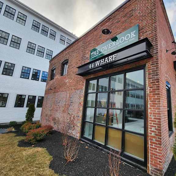 the overlook 44 wharf is a modern building with a brick facade and large glass windows.