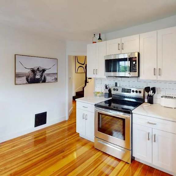 a kitchen with white cabinets and a wooden floor.