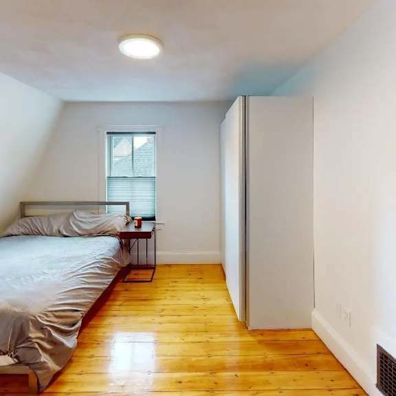 a bedroom with a bed, a nightstand, and a window.