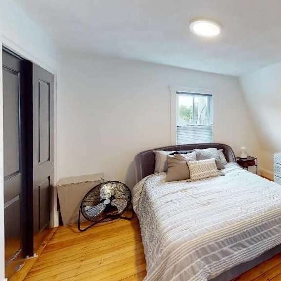 a bedroom with a bed, a couch, and a fan.