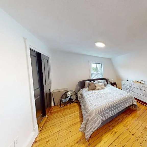 a bedroom with a bed, a chair, and a fan.