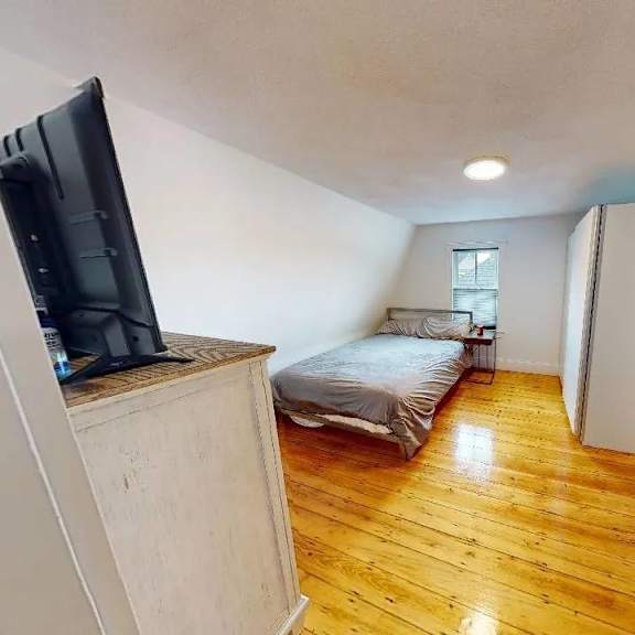a room with a bed, a television, and a window.