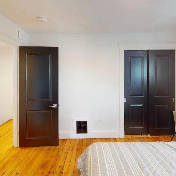 a bedroom with a bed, two doors, and a fan.