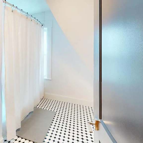 a white toilet sits next to a white shower curtain in a bathroom.