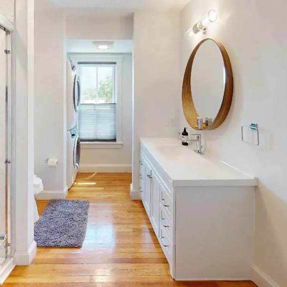 a bathroom with a white vanity and a round mirror.