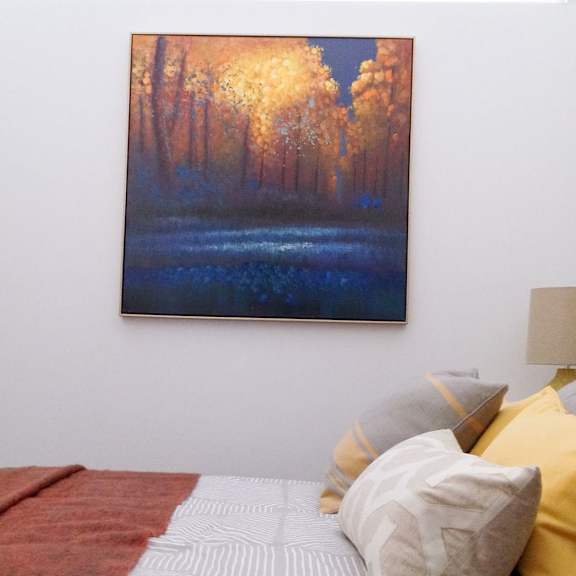 a bedroom with a bed, pillows and a painting on the wall.