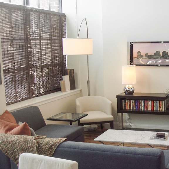 a living room with a grey couch and a painting on the wall.