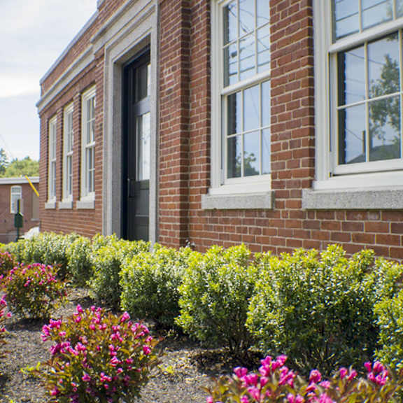 a red brick building with a flower bed in front.