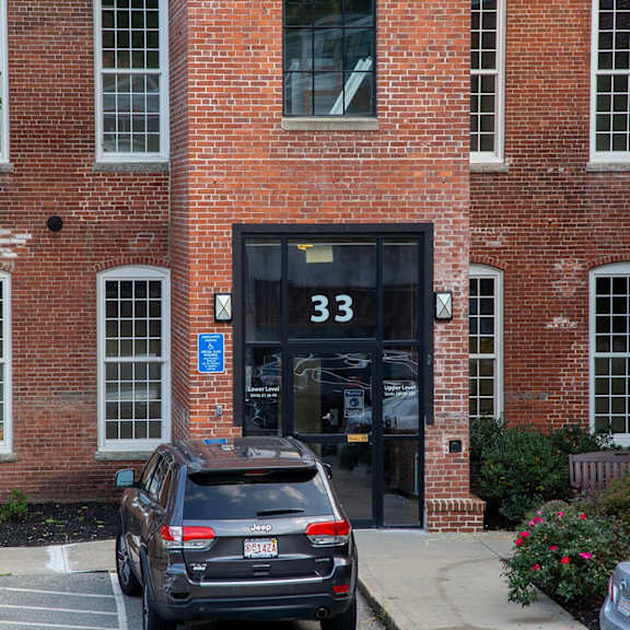 a black car is parked in front of a brick building with the number 33 on the door.