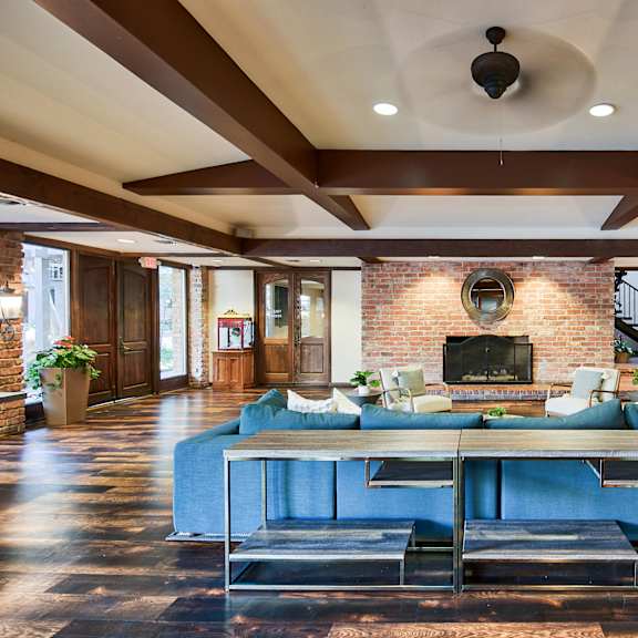 a large blue couch sits in the middle of a spacious room with a brick fireplace at the meadows apartments, culver city , ca 90230