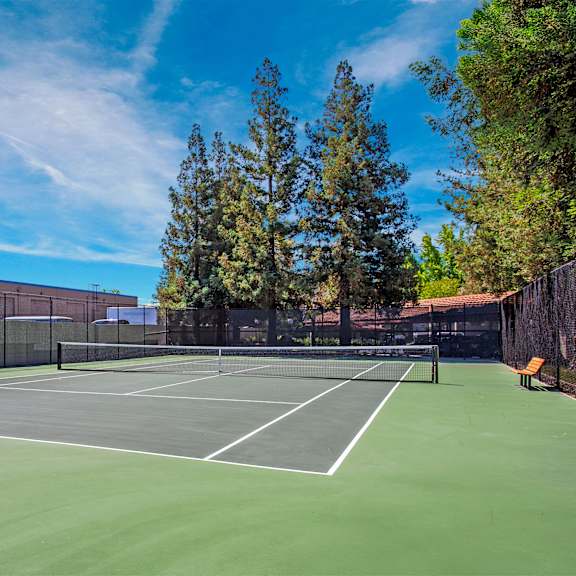 a tennis court surrounded by a fence and trees at valley plaza villages, california, 94566