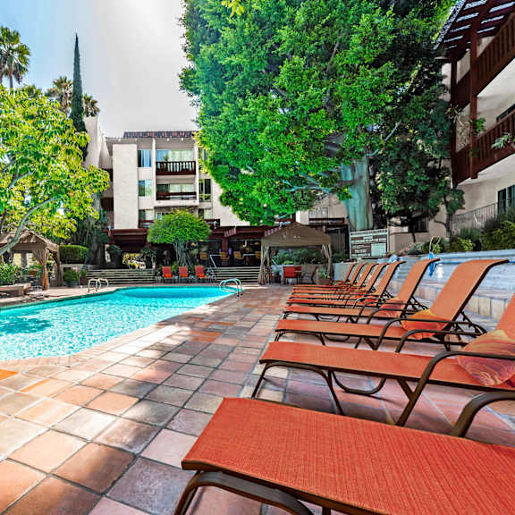 a pool surrounded by trees and chairs at mediterranean village west hollywood, west hollywood, 90069