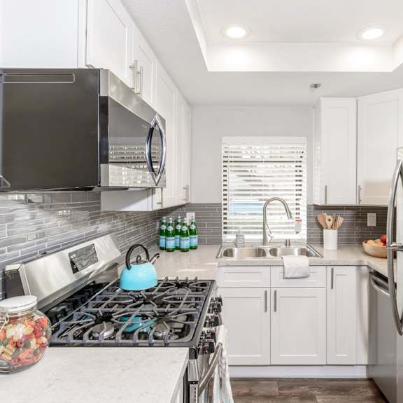 a small kitchen with stainless steel appliances and white cabinets at sendero huntington beach, california