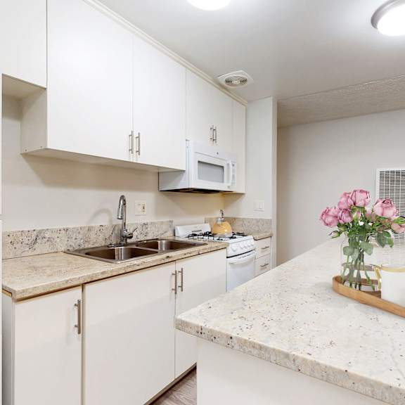 a kitchen with white cabinets and granite counter tops at casa granada, los angeles, ca