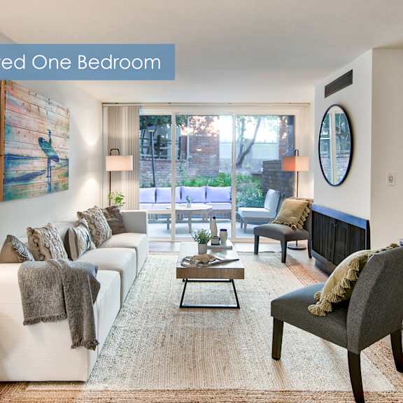 a renovated one bedroom apartment with a white couch, a coffee table, and a large window at the meadows apartments, culver city , ca 90230