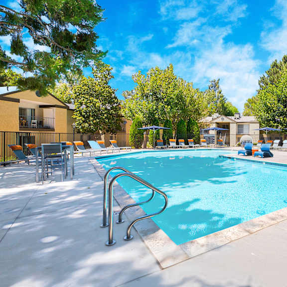 a large swimming pool surrounded by trees and lounge chairs at mountain vista, victorville, ca