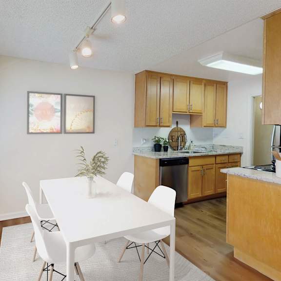 a white dining table with four chairs is in a kitchen with wooden cabinets at pleasanton glen apartments, pleasanton, california