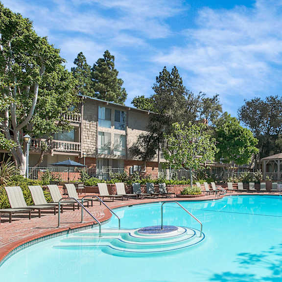 a large swimming pool surrounded by lounge chairs and trees at the meadows apartments, culver city , ca 90230