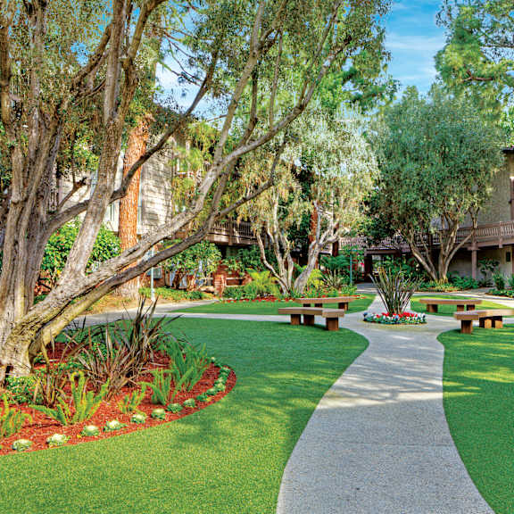 a walkway in a park with benches on either side at the meadows apartments, culver city , ca 90230