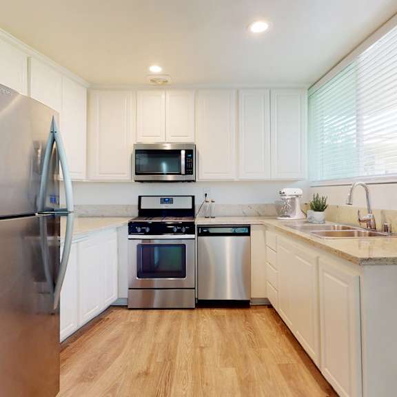 a modern kitchen with a stainless steel refrigerator and white cabinets at sunset barrington gardens, los angeles, 90049