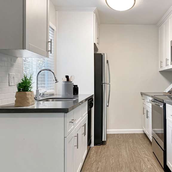a kitchen with white cabinets and black countertops at valley plaza villages, california, 94566