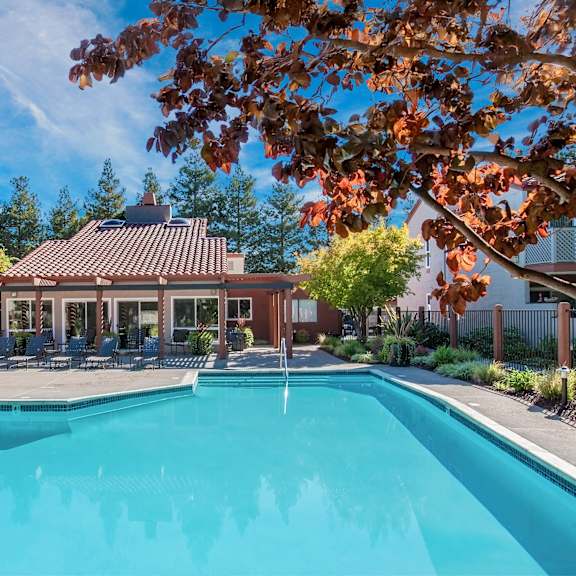 a swimming pool surrounded by trees and a building with a red roof at valley plaza villages, california, 94566