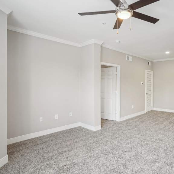 Thumbnail 3 of 6 an empty living room with a ceiling fan and a kitchen at The Verandah, Texas, 78726