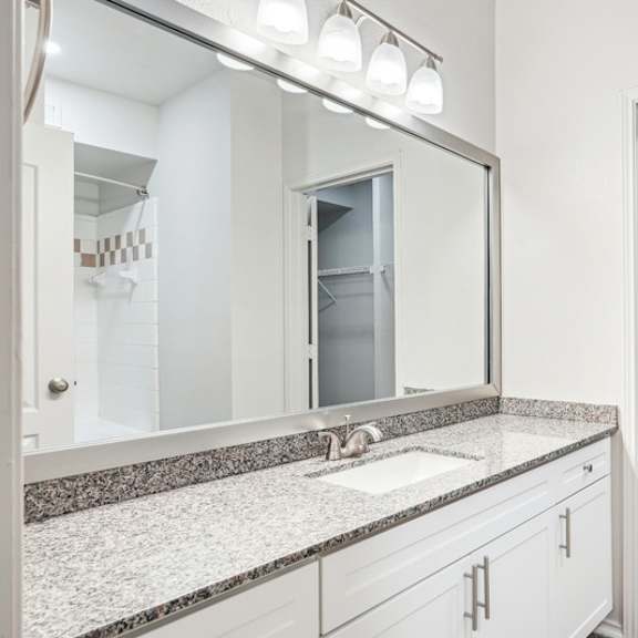 Thumbnail 16 of 16 A bathroom with a sink, mirror, and a white door.