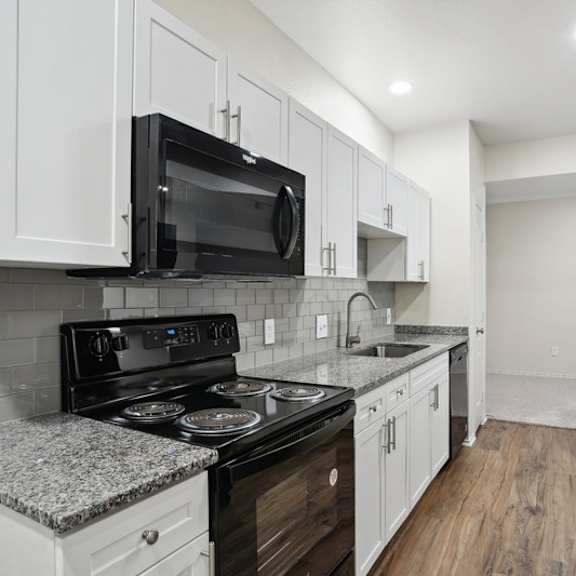 Thumbnail 6 of 16 A kitchen with black appliances and white cabinets.