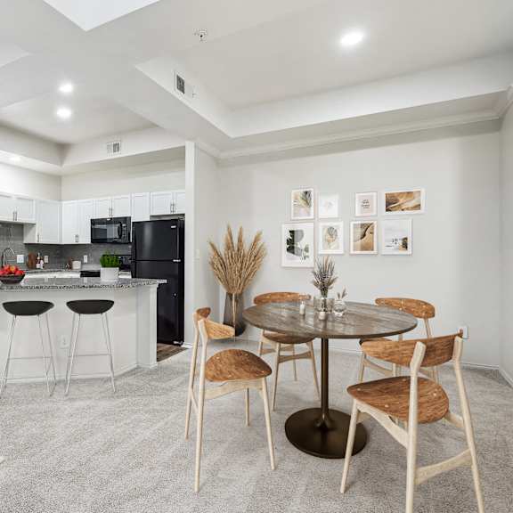Thumbnail 3 of 16 a living room with a kitchen and a dining table at La Ventura Apartments, Plano, Texas