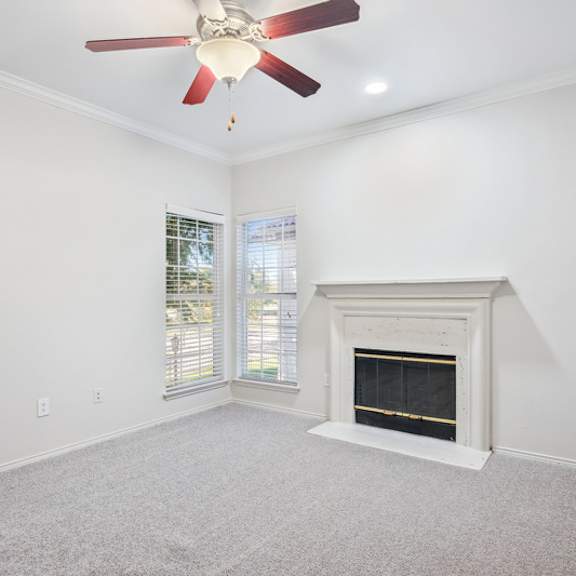 Thumbnail 15 of 16 A room with a fireplace and a ceiling fan.