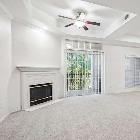 Thumbnail 11 of 16 A spacious living room with a fireplace and a ceiling fan.