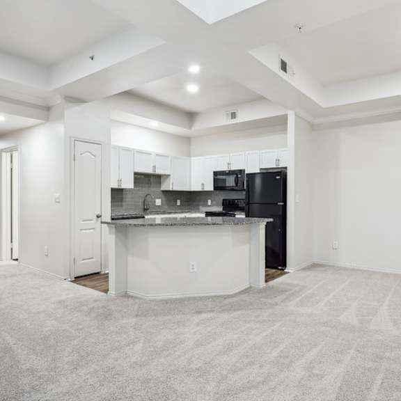 Thumbnail 10 of 16 A spacious kitchen with a bar area and a carpeted floor.