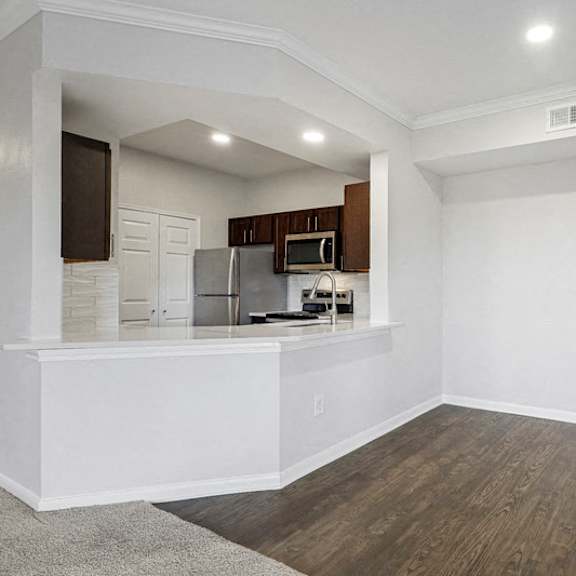 Thumbnail 5 of 10 an empty living room with a kitchen in the corner at The Legends at Eagle Mountain Lake, Fort Worth, TX