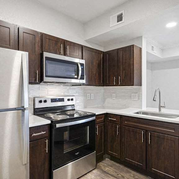 Thumbnail 2 of 10 a kitchen with wooden cabinets and stainless steel appliances at The Legends at Eagle Mountain Lake, Fort Worth, TX, 76179
