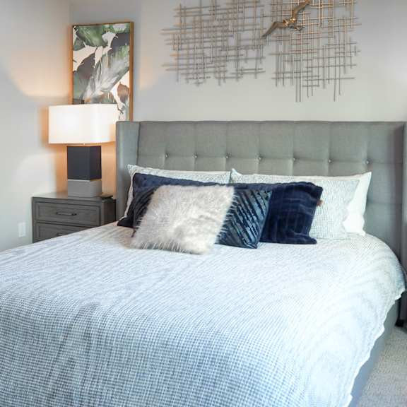 3 bedroom model master bedroom with a bed with pillows and a grey headboard at the hamilton apartments in dallas, tx
