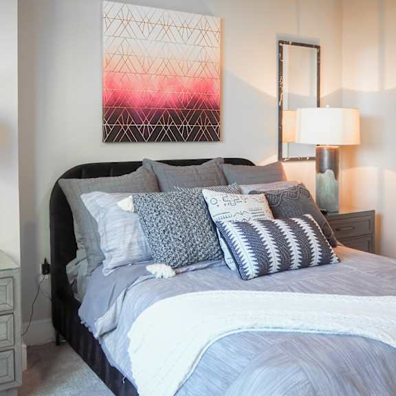 3 bedroom model third bedroom viewing a bed with pillows and a painting on the wall at the hamilton apartments in dallas, tx